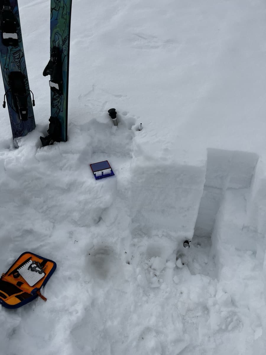 Snowpit excavated for dataset collection, with skis and sampling kit